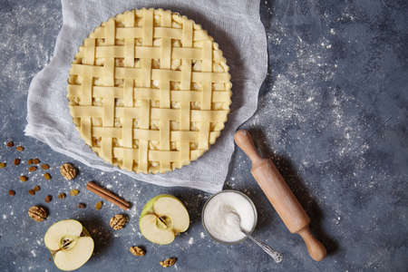 Apple pie tart homemade American traditional autumn sweet pastry baked food cooking recipe with ingridients, rolling pin, egg yolk, sugar flat lay on blue vintage background, top viewの写真素材
