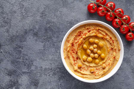 Hummus middle eastern dip paste close up with paprika, tahini, and olive oil, healthy diet natural vegetarian snack protein food. Traditional mediterranean appetizer on blue tableの写真素材