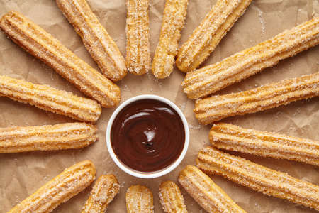 Churros traditional Spain breakfast or lunch street fast food baked sweet snack dessert with chocolate on rustic decorative parchment paper background. Flat lay top viewの写真素材
