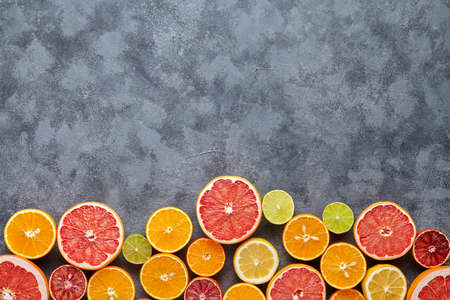 Different citrus fruit frame on dark grey concrete table. Fruit food background. Healthy eating and diet. Antioxidant, detox, dieting, clean eating, vegetarian, fitness or healthy lifestyle conceptの写真素材