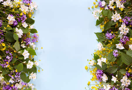 Floral summer gardenbackground on a blue table with lilac, yellow wildflowers and jasmine. View from above. Summer mood. Flat lay. Copy space for text.の写真素材