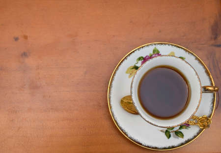 Topview of black tea in the vintage tea cup on the wooden floorの素材