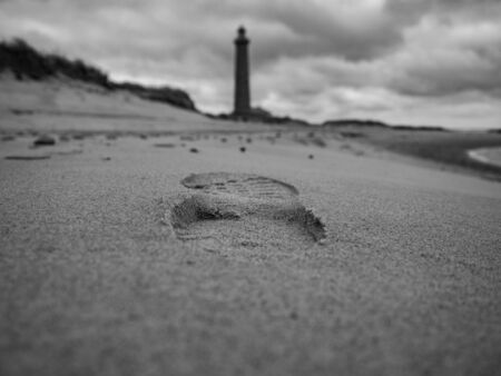 Unique tread on the beach sand on a cloudy day with a lighthouse in the background