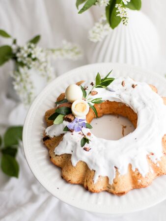 Kulich Traditional Easter sweet bread decorated with green leaves, flowers and a white egg a candy...