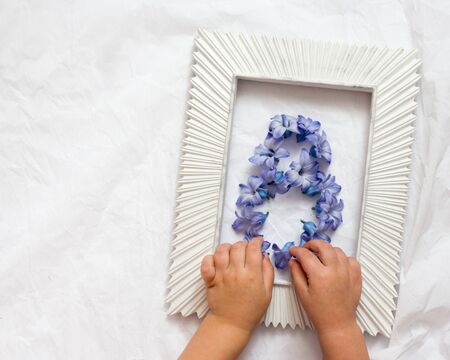 the childrens hands make eight of the flowers of blue hyacinth flowers for mom on International Womens Day. greeting card, place for an inscription, flat lay, copy space, top viewの写真素材