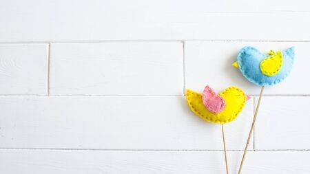 Spring home decor. Easter concept. Handmade yellow and blue felt birds on sticks on white background.flat lay,overhead,top view,copy space, place for text, bannerの写真素材