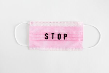 Flatlay with medical personal protective equipment with the inscription STOP for colds and flu prevention isolated on a white background. pink face masks.top view, copy space, place for textの写真素材