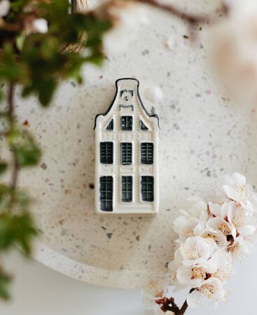 Flatlay, top view , selective focus house figure on a white marble surface with a blossoming cherry branch. stay home concept. spring, quarantine 2020の写真素材