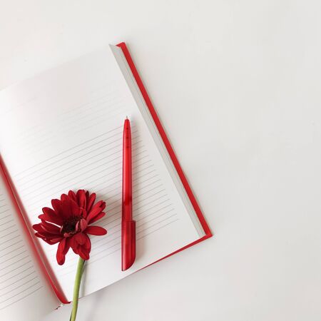 Flat lay, top view office desk writing desk. female desk workplace with red notebook, red pen and...