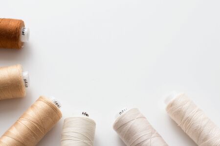 Colored sewing threads in nude colors on a white background, top view, flat lay, place for an inscriptionの写真素材