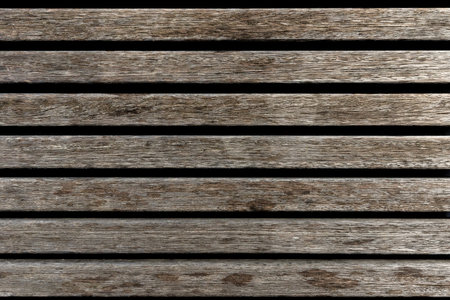 Full frame texture of old weathered wooden slats in a parallel pattern, rustic timber planks background with natural grain, overhead view of weathered wood siding for design