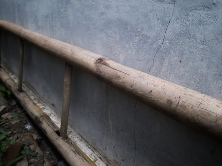 Defocused traditional bamboo ladder lay on the ground and grey cement wallの写真素材