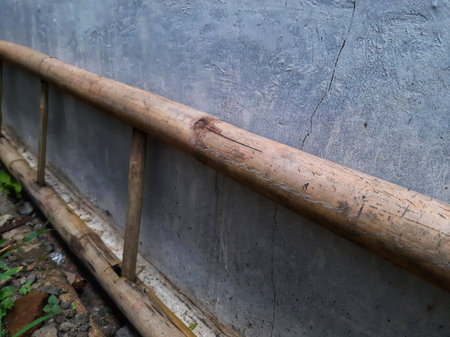Traditional bamboo ladder lay on the ground and grey cement wallの写真素材