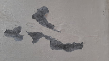 Broken Wall. Peeled white or cream color paint wall, so that the cement texture is visible. Abstract shape on the wall.の写真素材