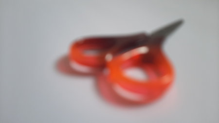 Blurred or unfocused or defocused single or one red orange brown scissors on isolated white backgroundの写真素材