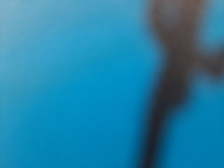 Blurred abstract black paint on solid blue backgroundの写真素材