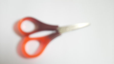Blurred or unfocused or defocused single or one red orange brown scissors on isolated white backgroundの写真素材