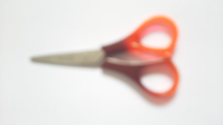 Blurred or unfocused or defocused single or one red orange brown scissors on isolated white backgroundの写真素材