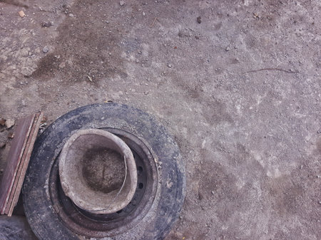 an unused car wheel, cement bucket, and ceramic tile on cement floor during constructionの写真素材