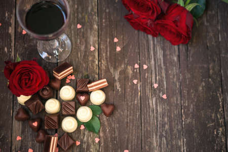 Old wooden background with red roses and chocolate pralines copy space top viewの写真素材