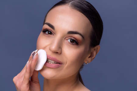 Beauty skin care. Beautiful happy woman removing face makeup using cotton pad. Close up portrait of healthy smiling female model with natural makeup touching perfect fresh soft skin, cleaning her face
の写真素材