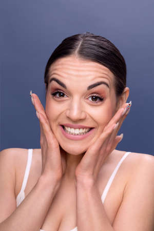 people, skincare and beauty skin concept - face of beautiful happy young woman with wrinkles on her...