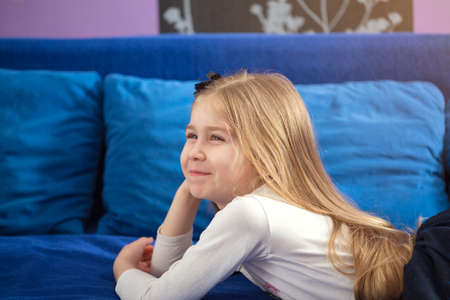 Young smiling little girl lying in bed at homeの写真素材