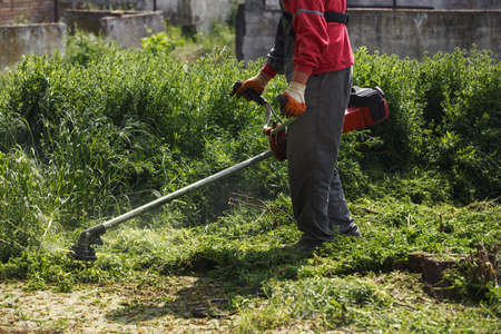 lawn mower worker cutting grass in green field background