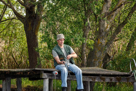 Fisherman with fishing rod on riverbankの写真素材