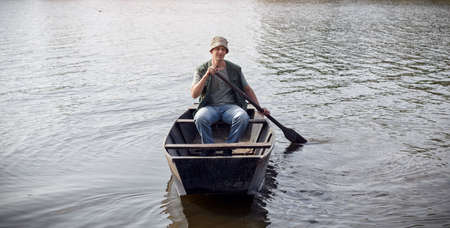 young man in fishing boat on river