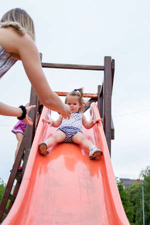 happy little adorable girl on slide at children playgroundの写真素材