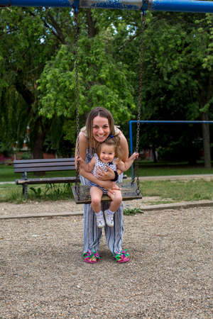 portrait of mother with daughter on swing at the playgroundの写真素材