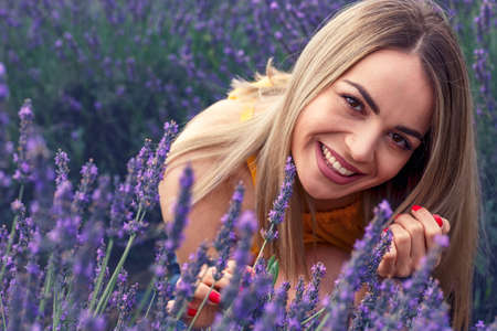 Young smiling woman in lavender field on beautiful summer dayの写真素材