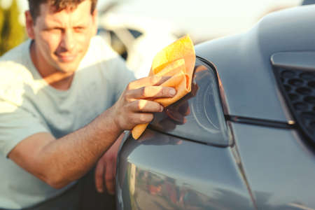 close up of man cleaning car with microfiber cloth, car detailing