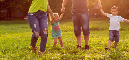 Happy young family playing on the grass in the parkの写真素材
