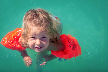 Funny cute little girl swims in a poolの写真素材