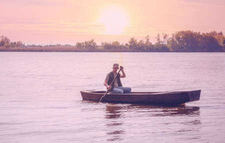 fisherman fishing-man catching fish in boat at sunsetの写真素材
