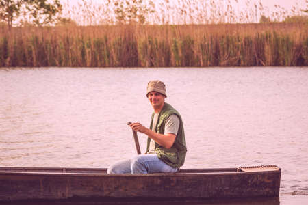 portrait of young fisherman in small boat on fishing dayの写真素材