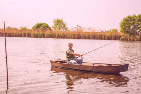 sport river fishing- man catching fish in boatの写真素材