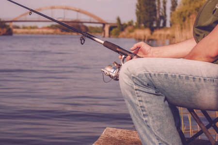 Fishing on the lake. Fisherman holding fishing rod with reelの写真素材