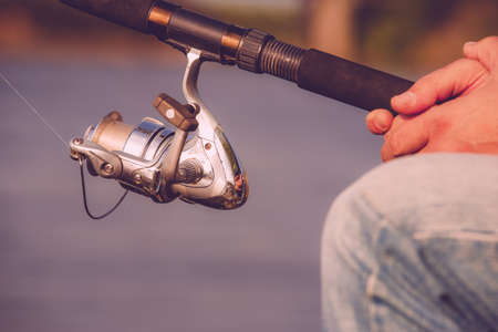 Fishing on the lake. Spinning reel and background of lake Fisherman holding fishing rodの写真素材