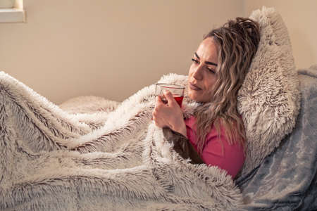 hot tea with lemon in bed- ill woman, Drinking herbal tea. Vitamins and hot tea for flu. Woman Caught Cold. Virus.の写真素材