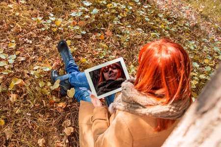 Young Woman with digital tablet in autumn parkの写真素材