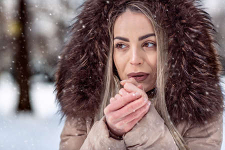 young woman in winter snow day blow on her cold hands close-upの写真素材