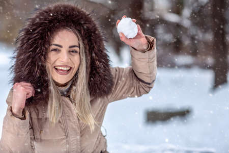 Smiling young girl playing snowball fight on the winter snow day