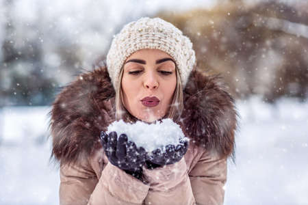 Winter young woman blowing snow in snowy day in winter time at nature.の写真素材