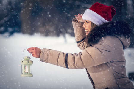 beautiful woman on winter forest with lantern âwinter holidays, Christmas and people conceptの写真素材