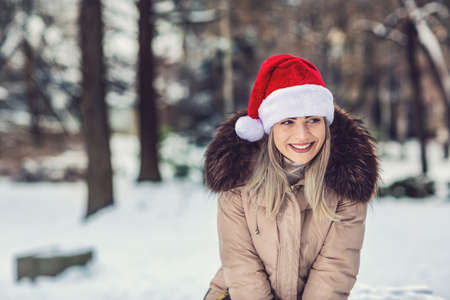 Christmas time - young smiling woman with Santa hat winter snow dayの写真素材