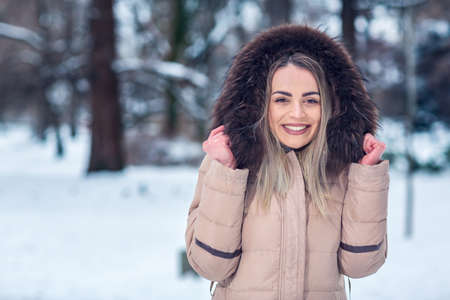Christmas time - portrait of Smiling young woman in wintertime outdoors. winter snow dayの写真素材