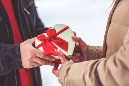 hand of guy giving his girlfriend Christmas present for holiday